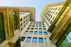 Architectural view of large building with textured wall, showcasing modern design and structural elegance against a clear blue sky.
